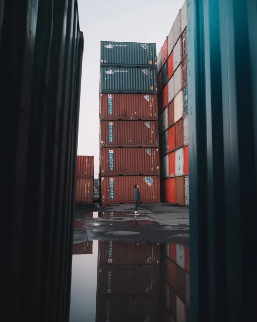 Stacked shipping containers with a reflection on the ground